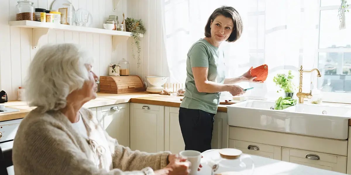 Frau hilft Seniorin im Haushalt