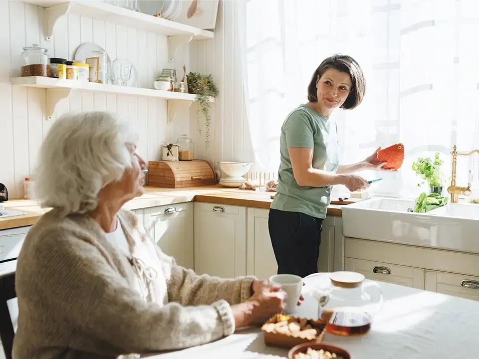Frau hilft Seniorin im Haushalt
