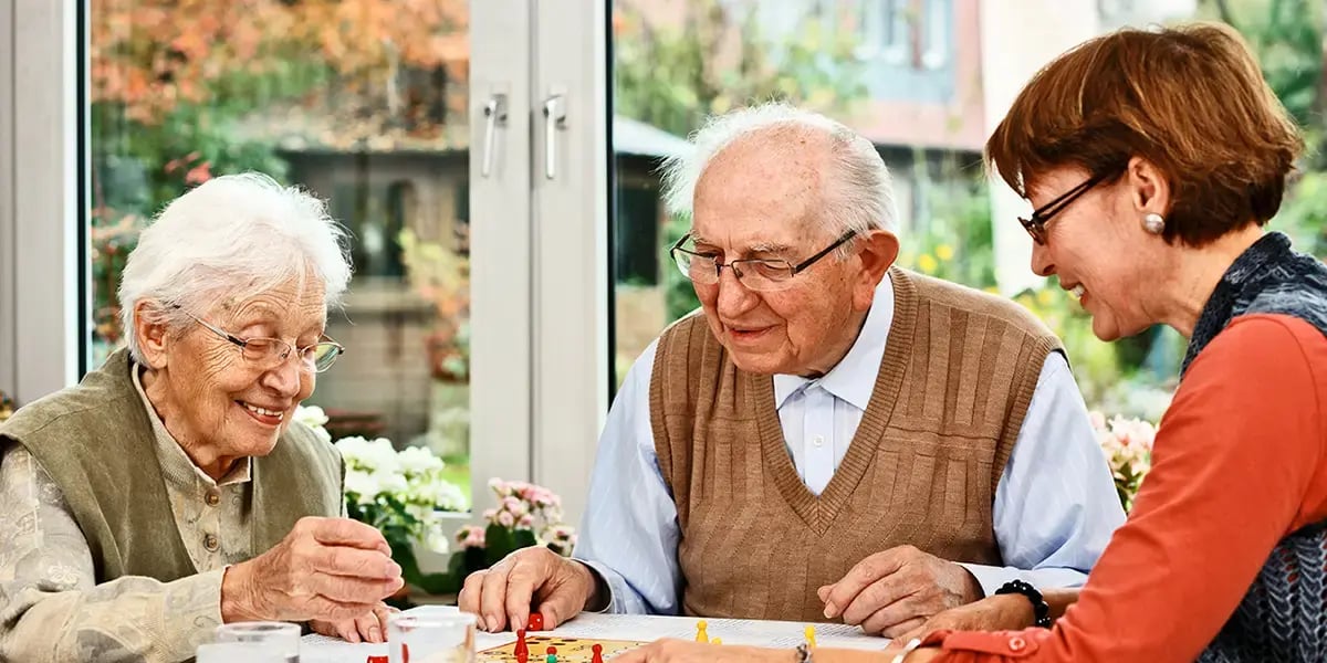 Seniorin spielt mit ihren Eltern Brettspiel