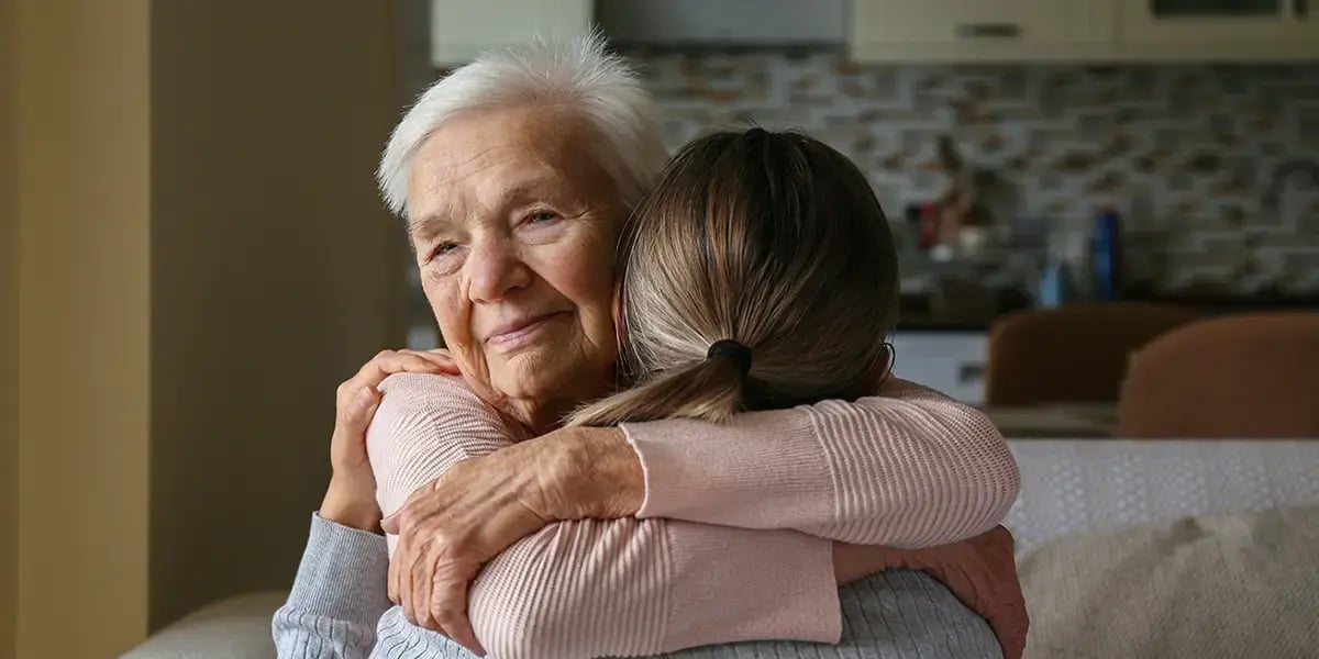 Frau umarmt pflegebedürftige Grossmutter