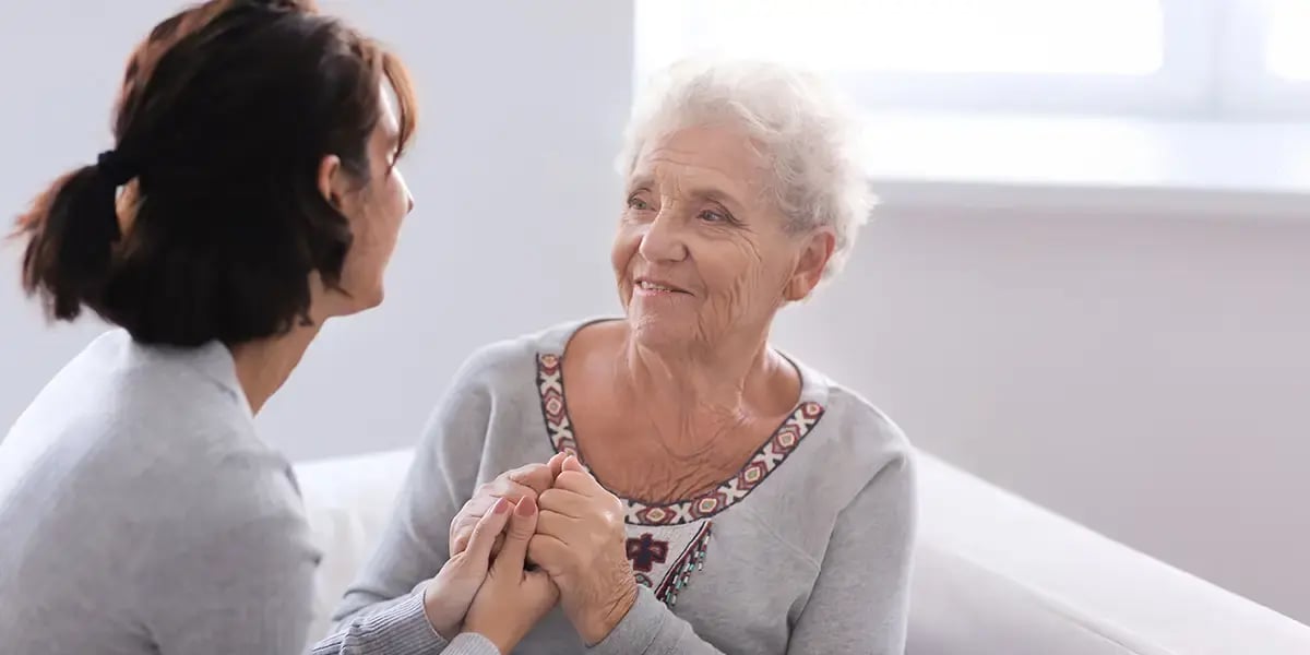 Angehörige hält Hand von Seniorin