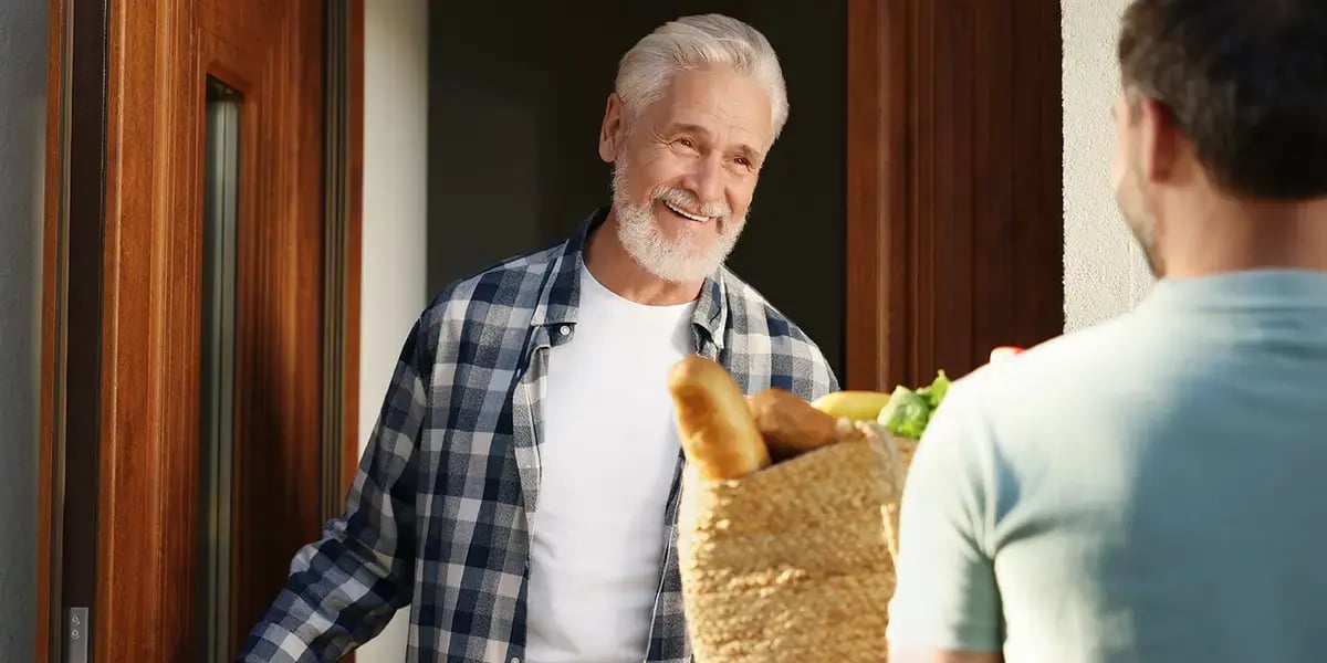 Mann überreicht Senior den Einkauf
