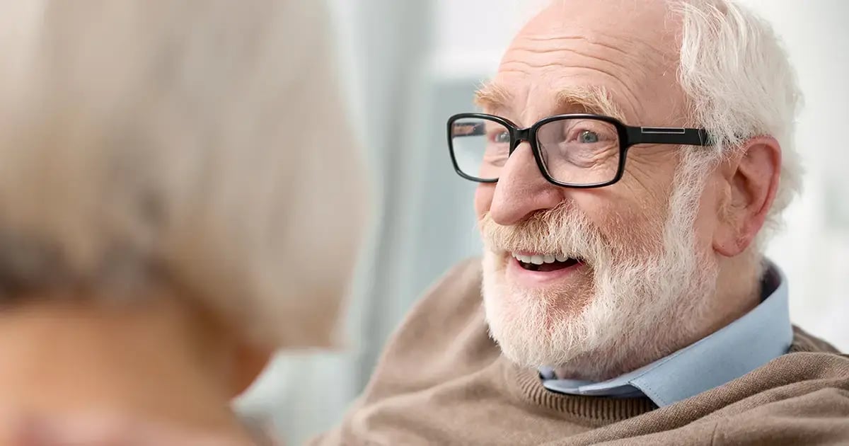 Senior lächelt eine Person an